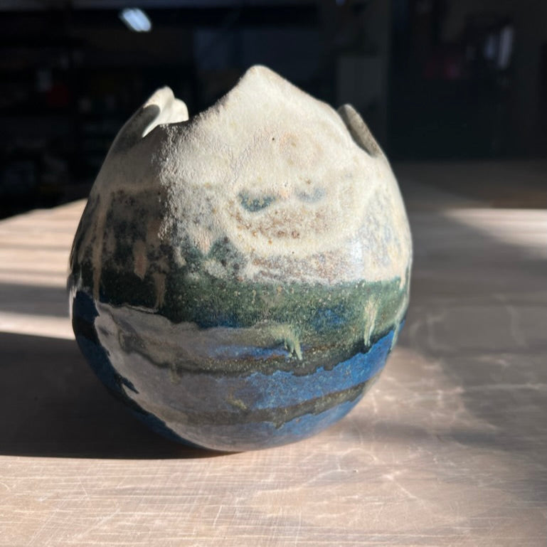 Ceramic vase with a landscape design on a wooden surface